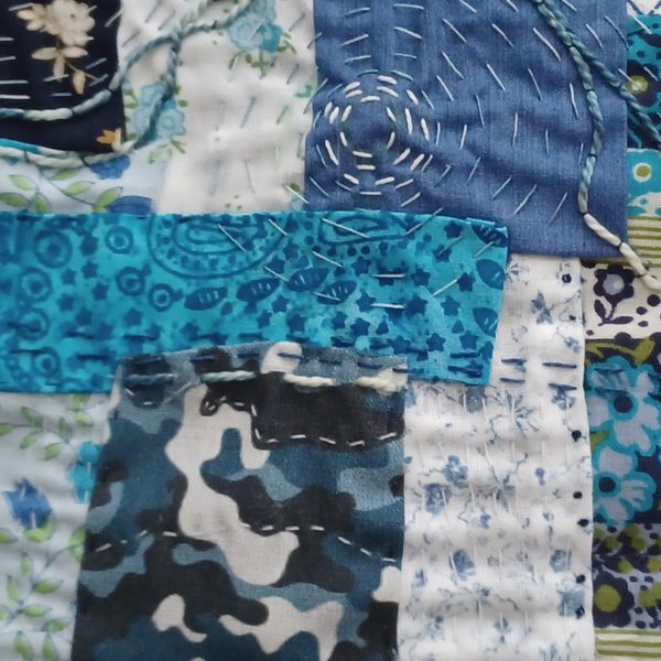 Several different blue fabrics layered and stitched together with Boro stitching.