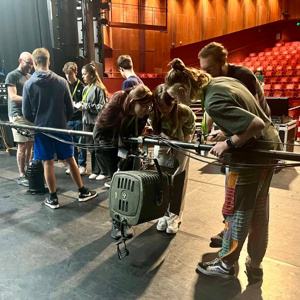A group of young people looking at various pieces of technical equipment on the Salisbury Playhouse stage.