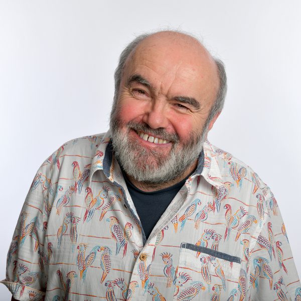 Comedian Andy Hamilton wearing a patterned shirt and smiling at the camera.