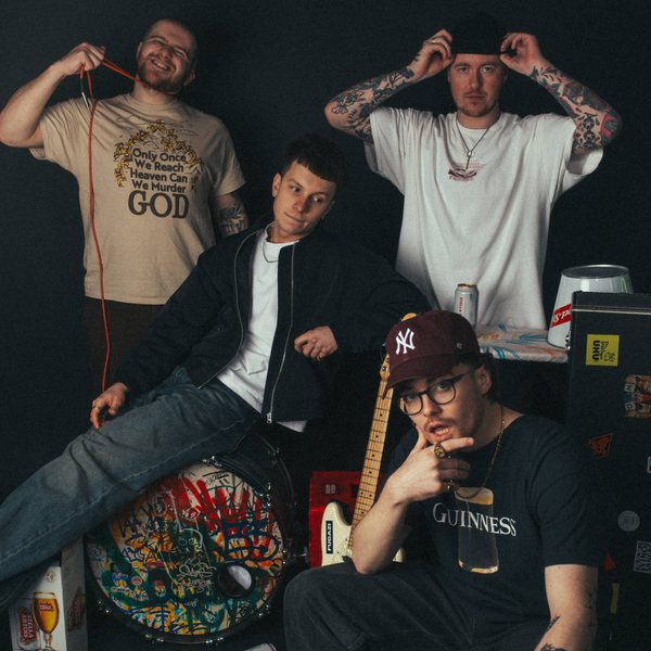 The four members of Carsick posing together with their instruments below and around them.