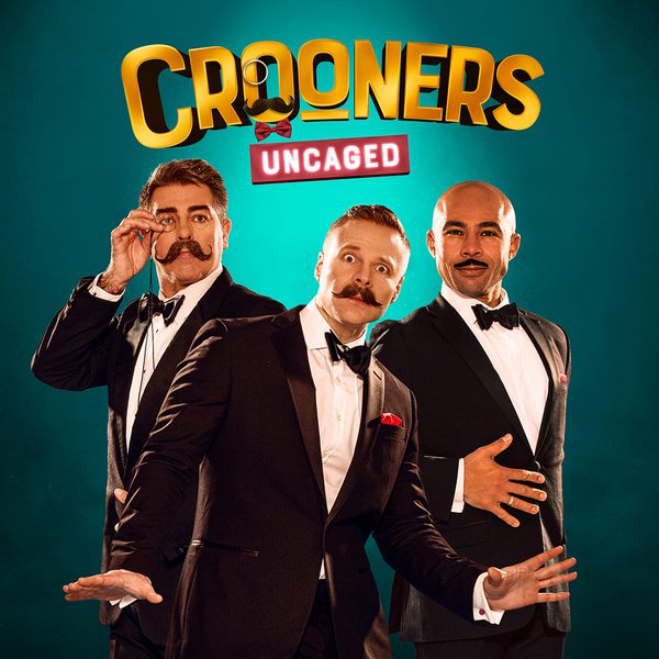 Three men in tuxedos pose against a dark green background. They all have mustaches and are smiling inquisitively at the camera. Above them is the title 'Crooners Uncaged' in bold, gold text.
