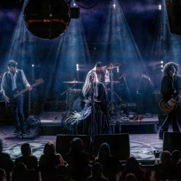 The band members of Fleetwood Back onstage performing, dressed as Fleetwood Mac.