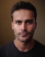A headshot of East is East cast member Danyal Ismail. He has short hair and stubble. He wears a t-shirt.