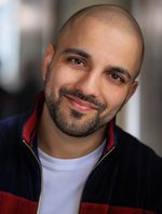 A headshot of East is East cast member Joeravar Sangha. He has a shaved head and stubble, and is wearing an open jacket over a t-shirt.