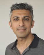 A headshot of East is East cast member Sushil Chudasama. He has short grey hair and is wearing a polo shirt.