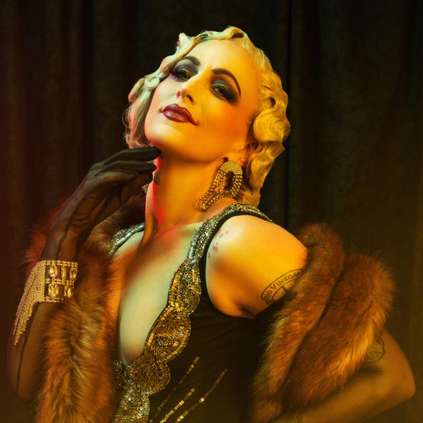 Burlesque artist Lena Lenman dressed in 1920s flapper attire and posing seductively to camera.