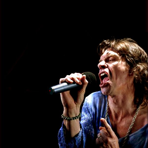 Mick Jogger performing onstage, singing into a microphone.