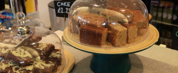 Café counter with cakes under glass domes and freshly baked scones.