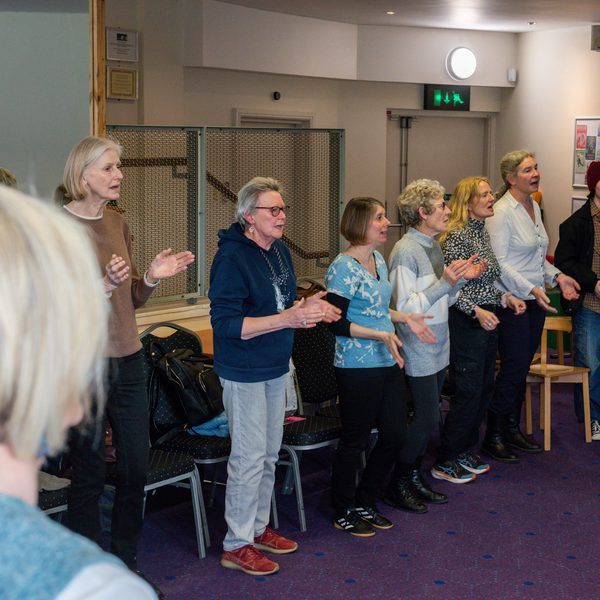 Several women singing and clapping in a workshop.