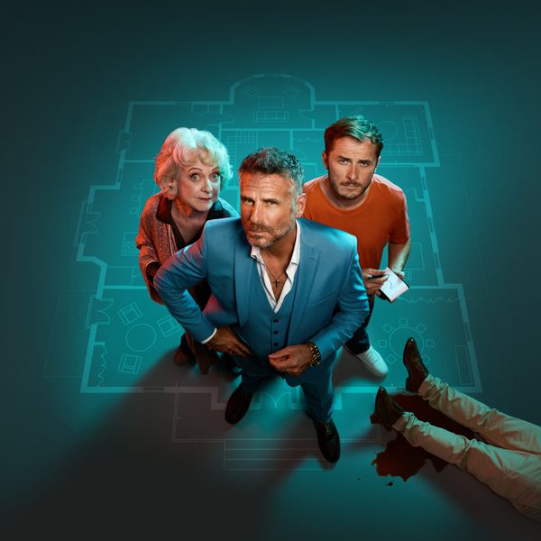 Jason Durr, Susie Blake and Max Bowden stood on a large teal blueprint facing the camera. The legs of a dead body are in the bottom right.