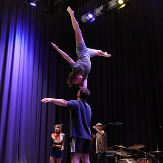 Two circus performers, one upside down balancing on top of the other.
