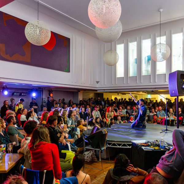 Pete Bearder performing on a small indoor stage to a rapt audience.