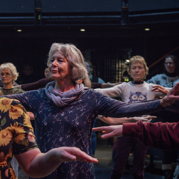 Several women moving in sync in a movement workshop.