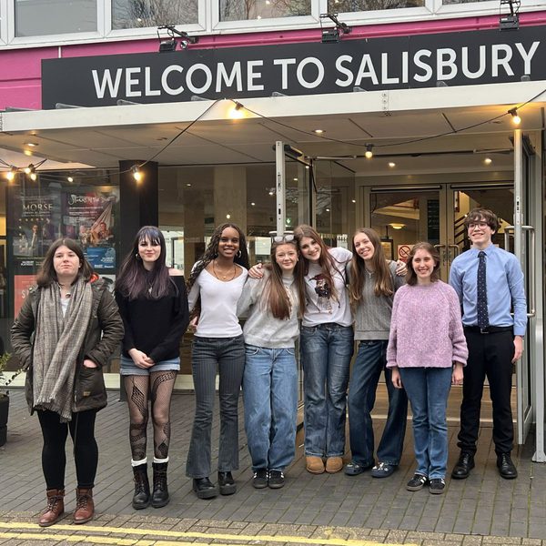 A group of eight young people pose in front of the entrance to Salisbury Playhouse. Text above the doorway reads Welcome to Salisbury.