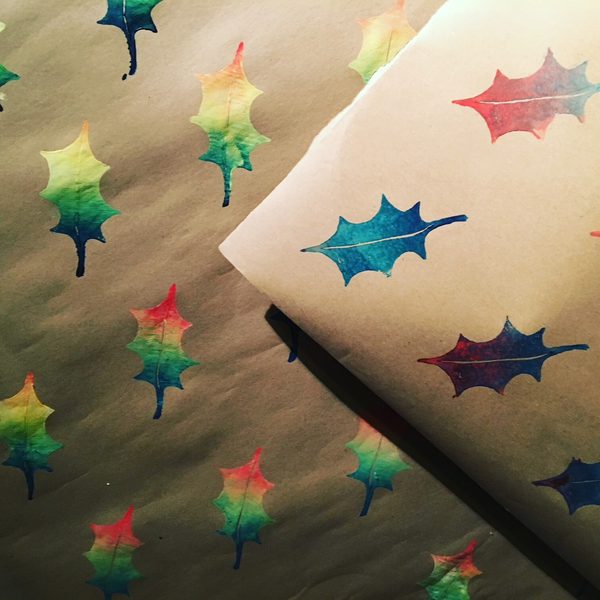 Brown wrapping paper with colourful holly leaves printed on it.