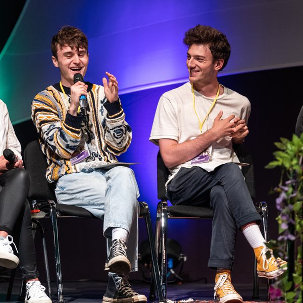 Two young people talking into microphones on stage.
