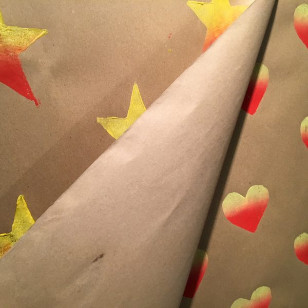 Brown wrapping paper with colourful stars and hearts printed on it.