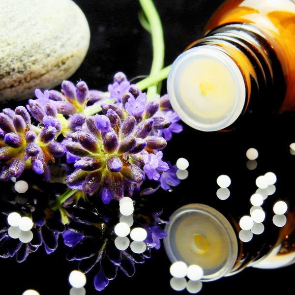 A bottle of essential oils next to a lavender sprig.