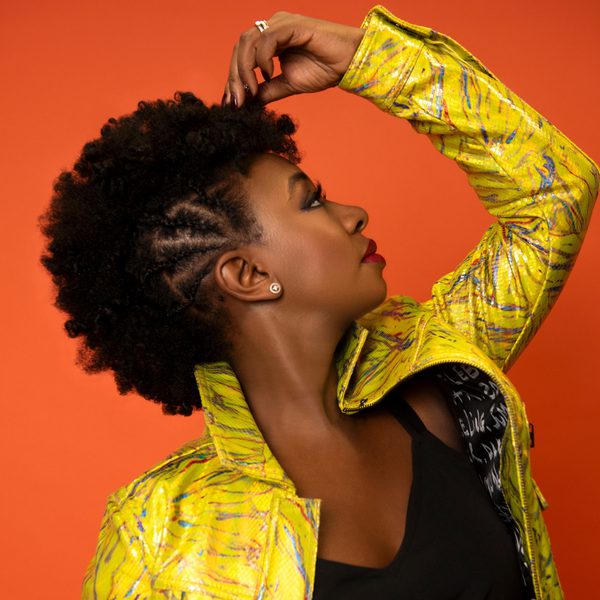 Saxophonist YolanDa Brown facing to the right with her arm raised above her head a la Michael Jackson.